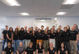 Group of people in matching black Layer Health t-shirts posing together in an office space.