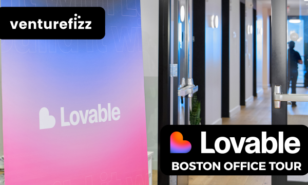 Vibrant Lovable banner beside a glass-door hallway, with a VentureFizz logo on a black rounded badge above left.
